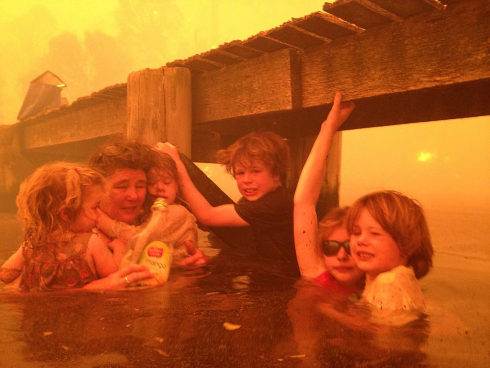 Тэмми Холмс и ее внуки укрываются под причалом во время лесного пожара в Австралии. Фото: Tim Holmes—AP