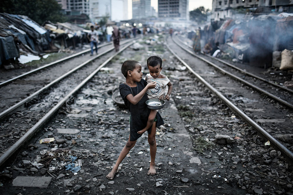 Девочка кормит своего брата в трущобах Кавран, ютящихся вдоль железнодорожных путей. Место съёмки: Дакка, Бангладеш. Номинация: Youth, Environment Category, 1 место. (Turjoy Chowdhury/2014 Sony World Photography Awards)