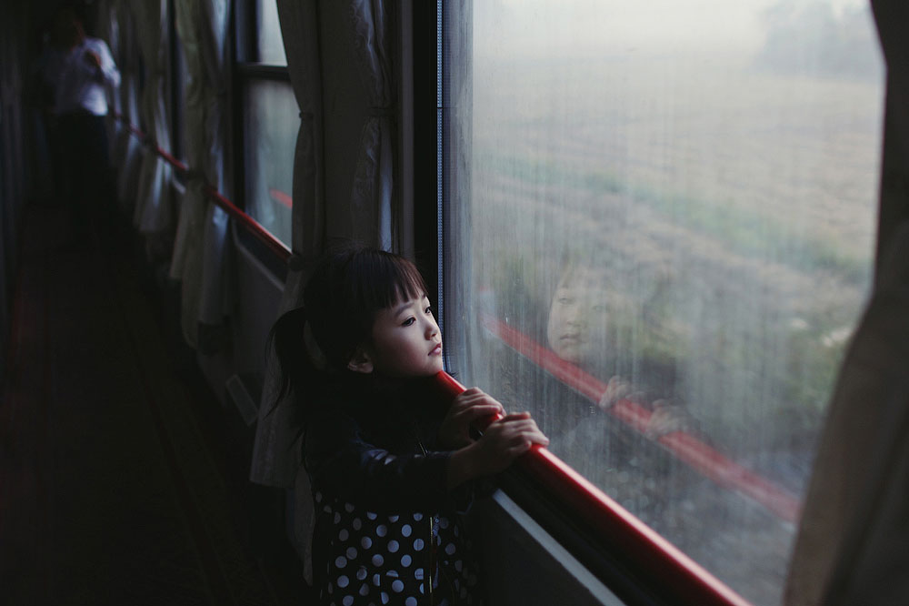Девочка смотрит в окно 24-часового поезда на проплывающий мимо пейзаж. Место съёмки: Китай. Номинация: Youth, Portraits, 1 место. (Paulina Metzscher/2014 Sony World Photography Awards)