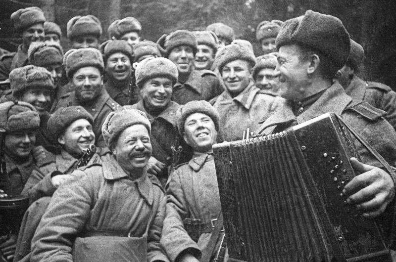 Перед штурмом города Великие Луки. Советские солдаты слушают игру на гармони-"трехрядке" своего товарища.  Январь 1943 года. Автор: Максимов