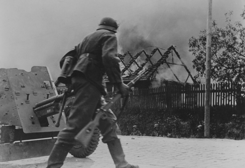 Немецкий солдат переходит улицу горящей советской деревни у 37-мм противотанковой пушки PaK 35/36. Фотография опубликована на обложке американского журнала Newsweek от 20 октября 1941 года. Источник: www.nationaalarchief.nl.