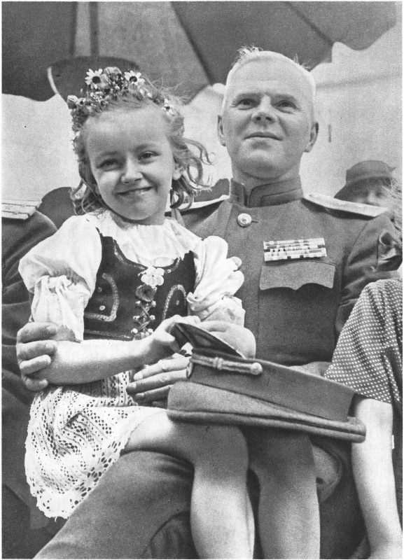 Чешская девочка сидит на коленях у генерала-лейтенанта Красной Армии во время праздника в Праге.