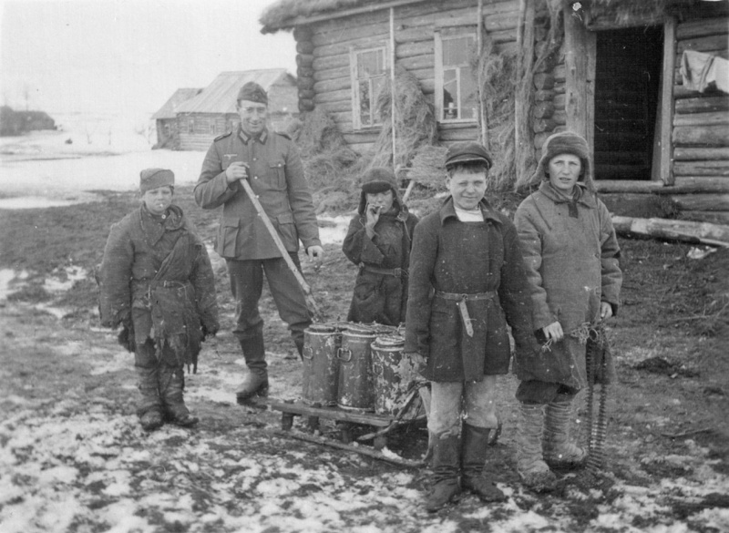 Немецкий солдат с детьми в оккупированной советской деревне. Два самых маленьких мальчика курят папиросы.