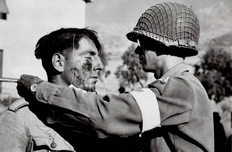 Медик из состава 48-го медицинского батальона 2-й бронетанковой дивизии армии США делает перевязку раненому немецкому солдату. Июль 1943.