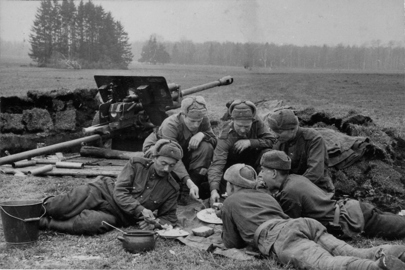 Советские артиллеристы обедают рядом с орудием на подступах к Берлину. Апрель 1945. 