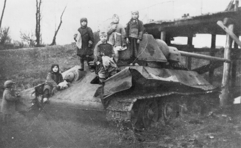 Дети на брошенном у моста советском танке Т-34-76. Фото не ранее осени 1942 года, так как танк оснащен башней-"гайкой", которую стали ставить с этого времени.