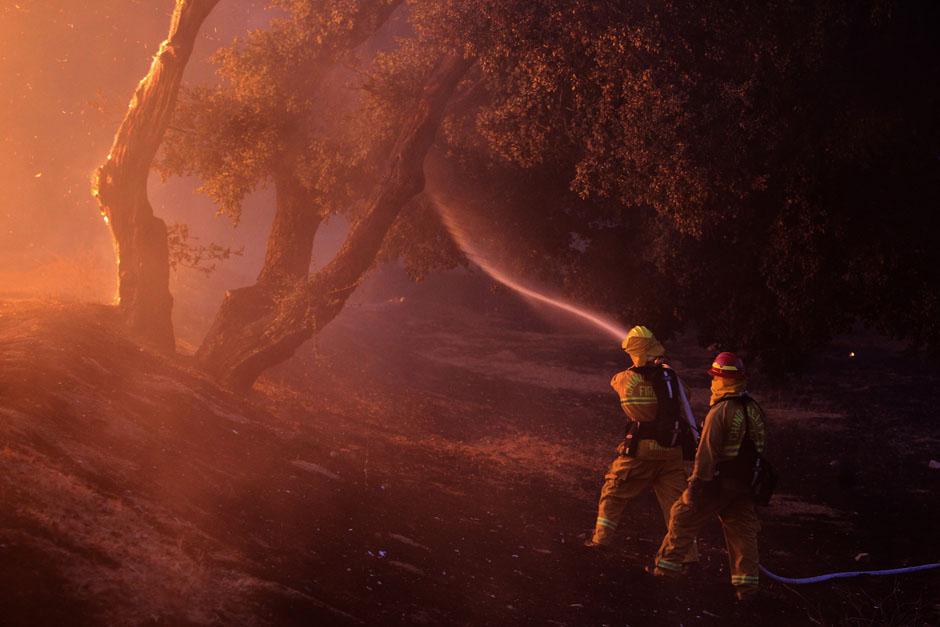Пожарные распыляют воду вблизи горящего дома. Калифорния, 7 августа 2013 г.